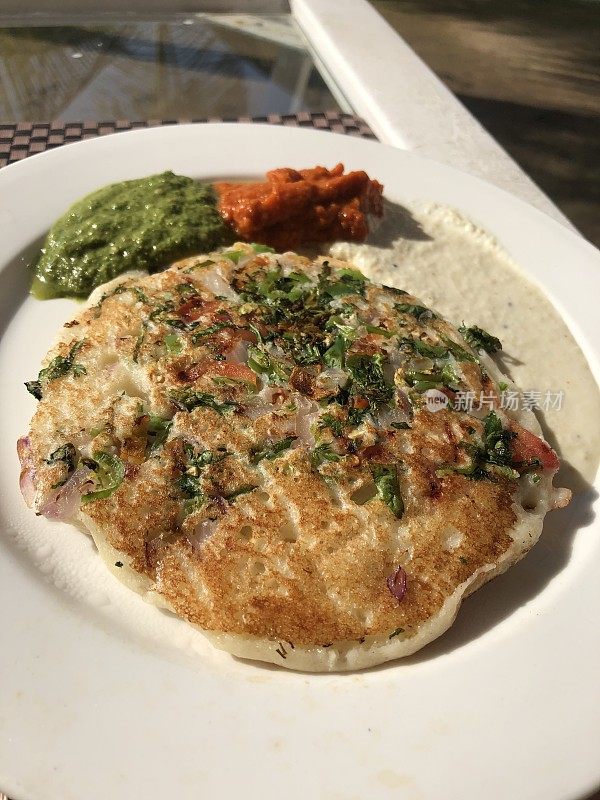 印度早餐的图片是油炸的uttapams，可口的煎饼面糊(Uttappa / Oothapam)像迷你披萨的照片，早餐有uttapams，番茄酱和酸辣酱蘸在白色的盘子里，新德里酒店餐厅